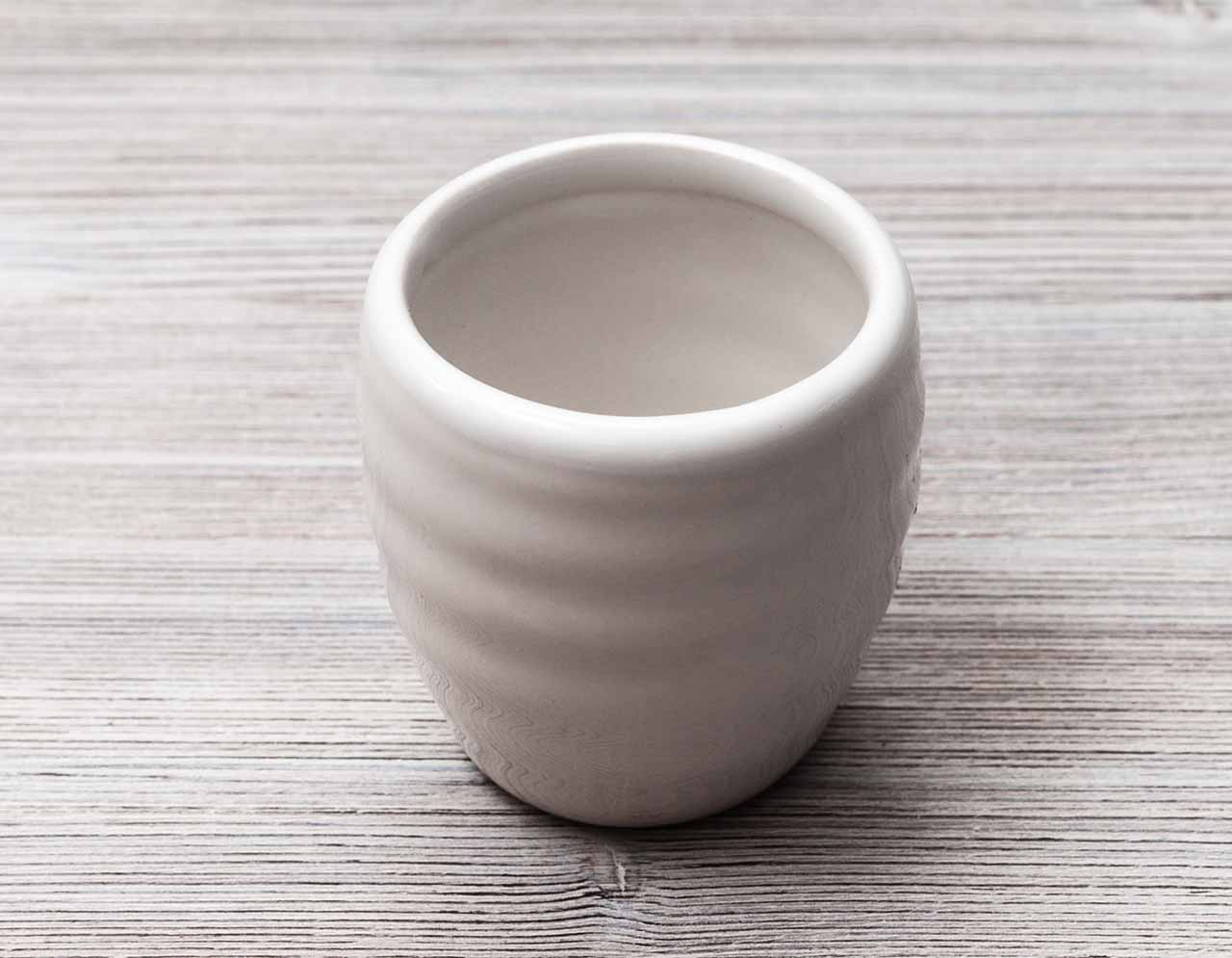 white cup for sake on gray brown wooden table